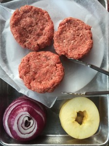 Burgers, onions, and apples ready to grill